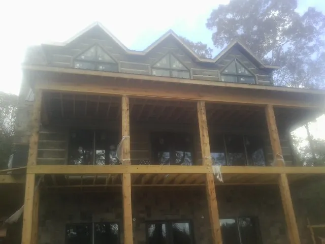 Dormers and porch framing on a large log home under construction — Roof Coating work by our crew in Mount Dora