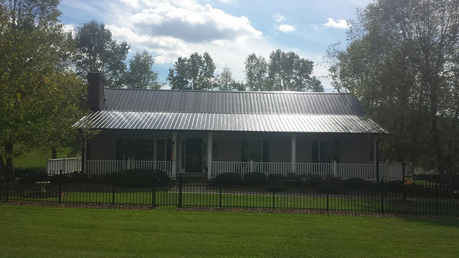 Gray metal roof on a brick ranch with a full width front porch — Gutter Guard Installation work by our crew in Mount Dora