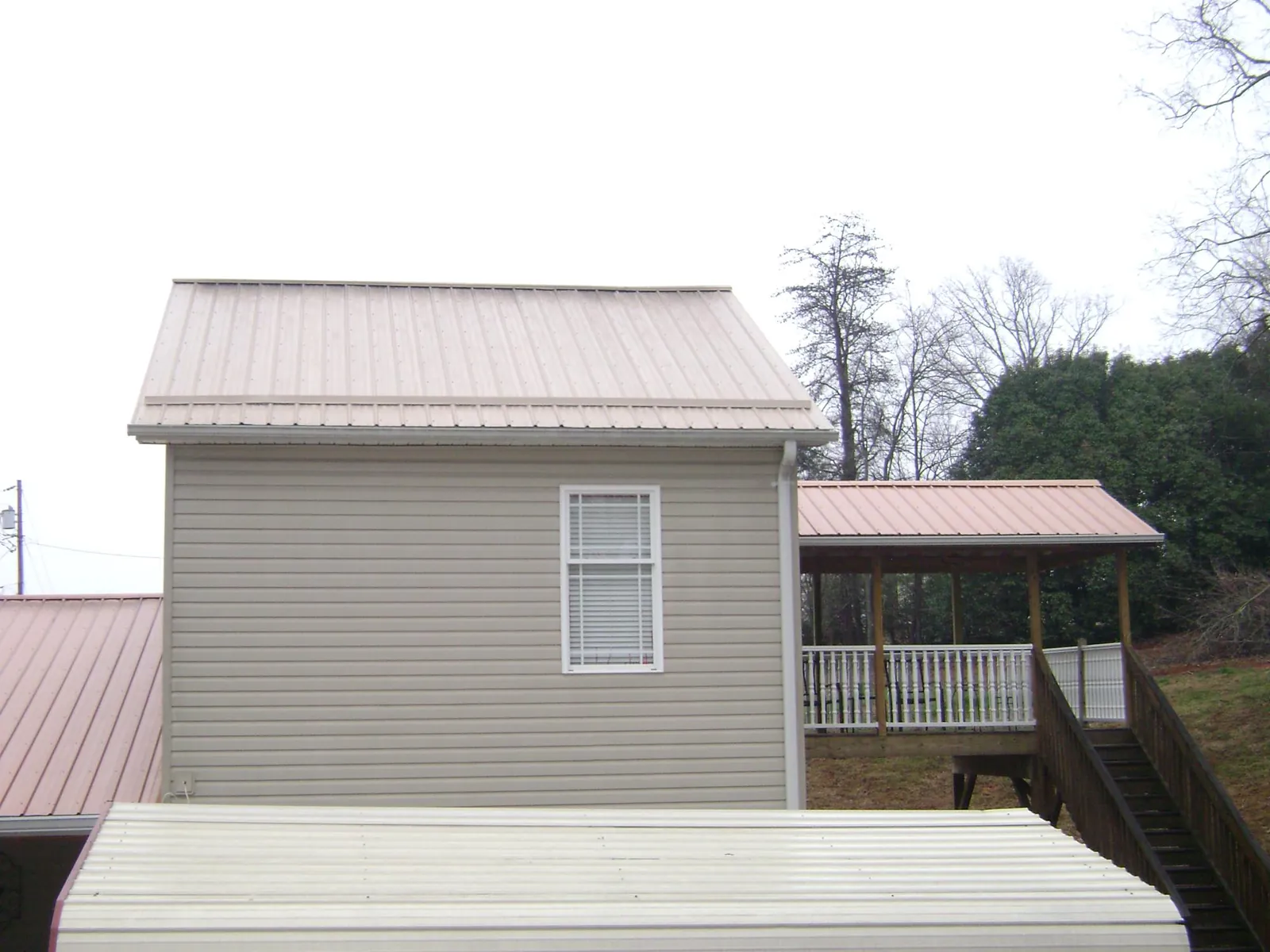 Tan metal roofs on a two story addition and attached porch, from a Roof Replacement job in Mount Dora